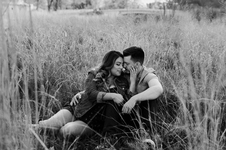 Engaged couple sitting in wild grasses