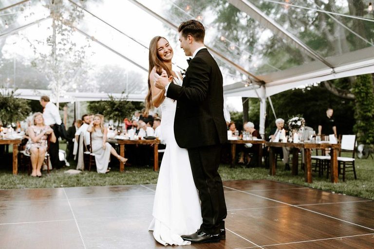 Bride and groom dancing under clear tent